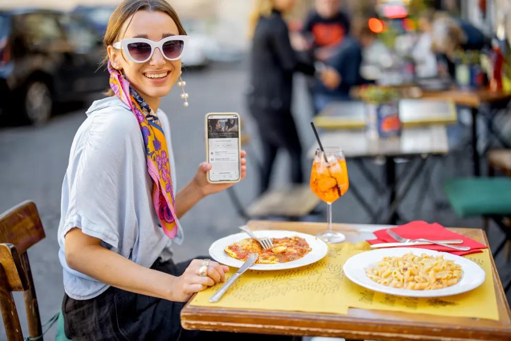 Eine Frau in einem Restaurant, die ihre Rechnung bequem mit einem QR-Code über ihr Smartphone begleicht.